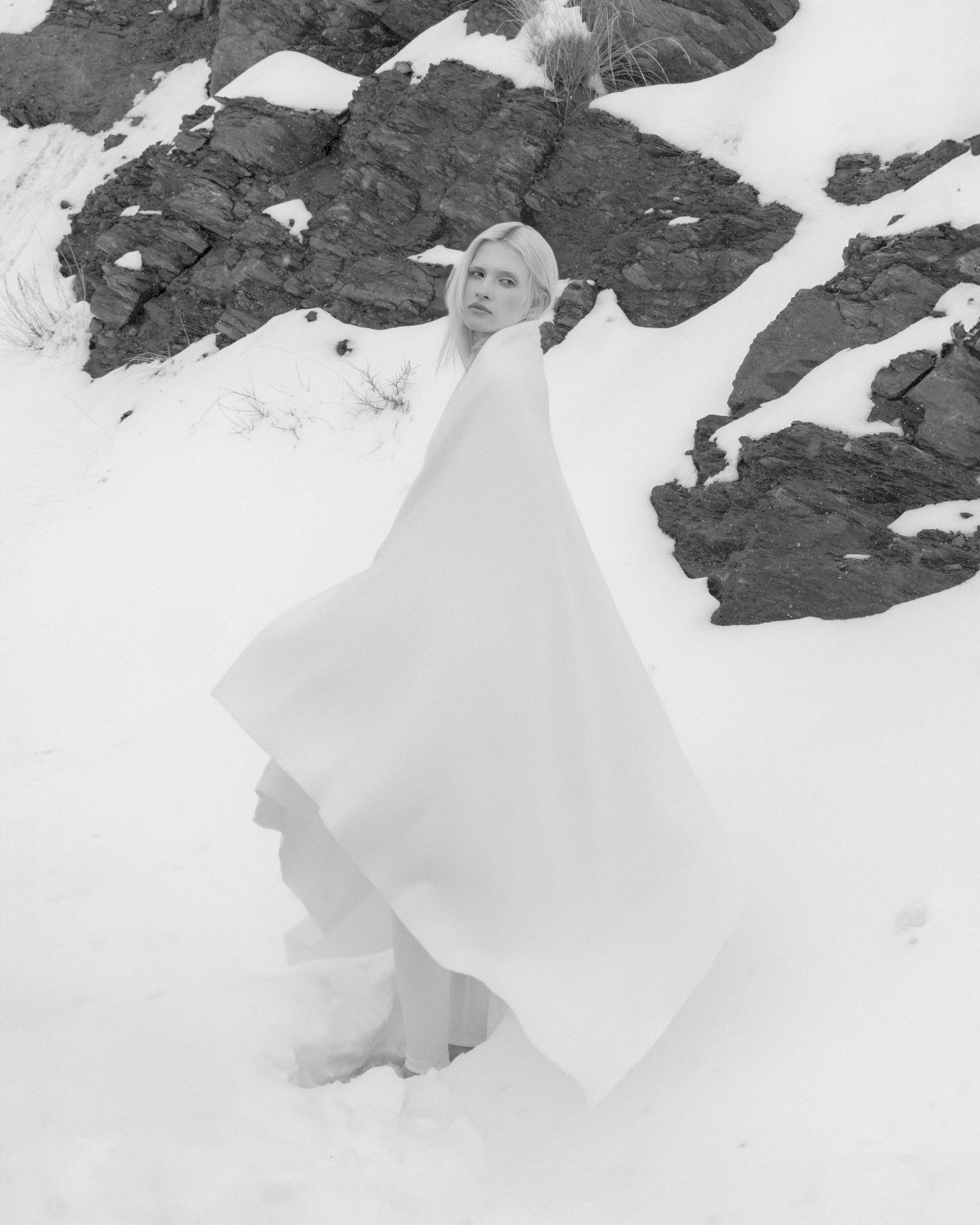 Woman with white hair, dancing in show with a white wool throw draped on her shoulders