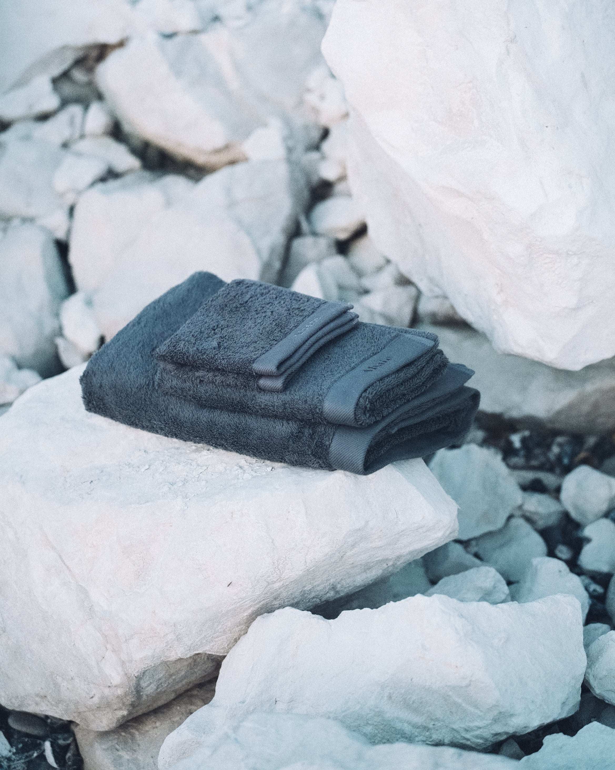 Close up of dark grey towels folden neatly on top of white rocks.
