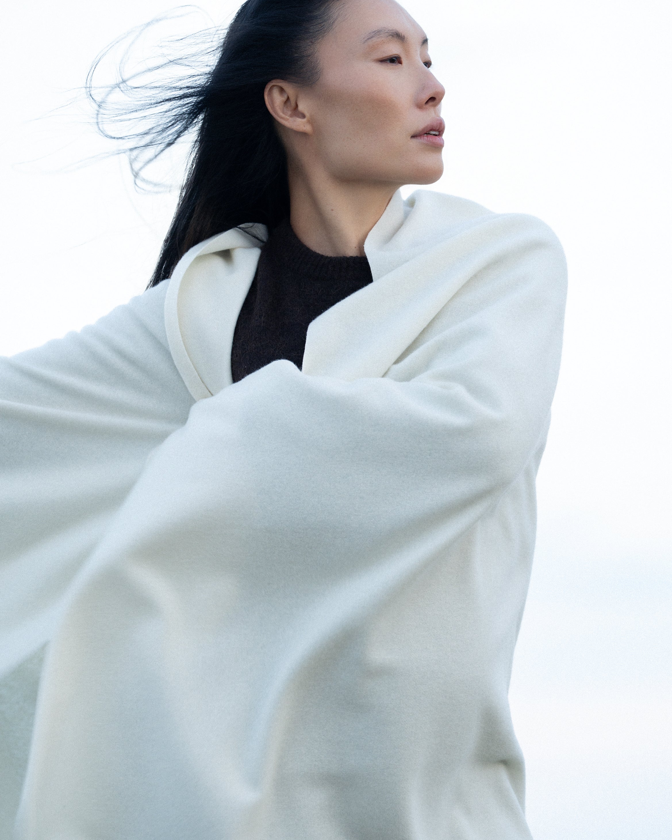 Woman with wind in her hair and a soft merino wool throw on her shoulders.