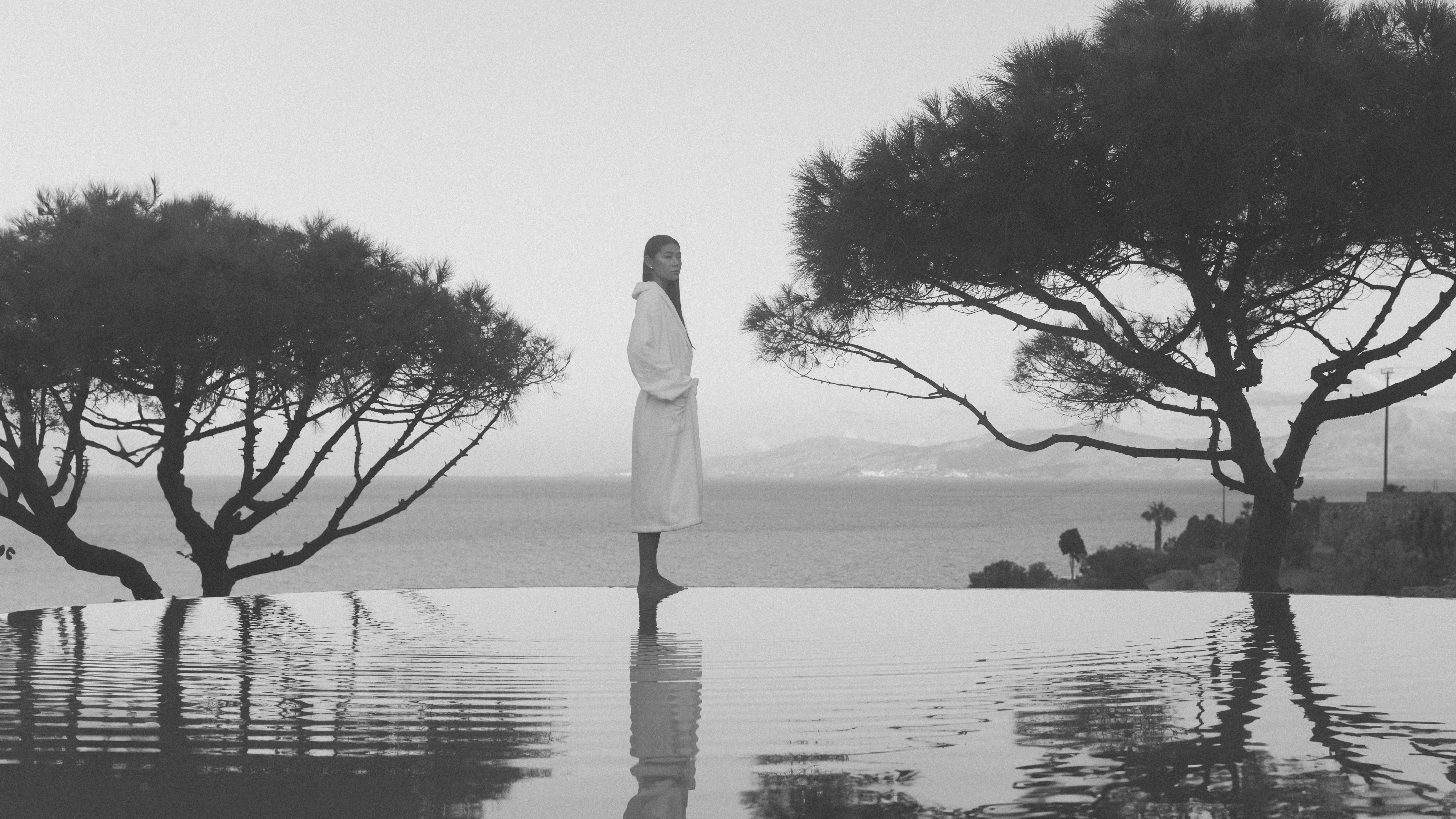 Woman standing next to pool overlooking the ocean behind her