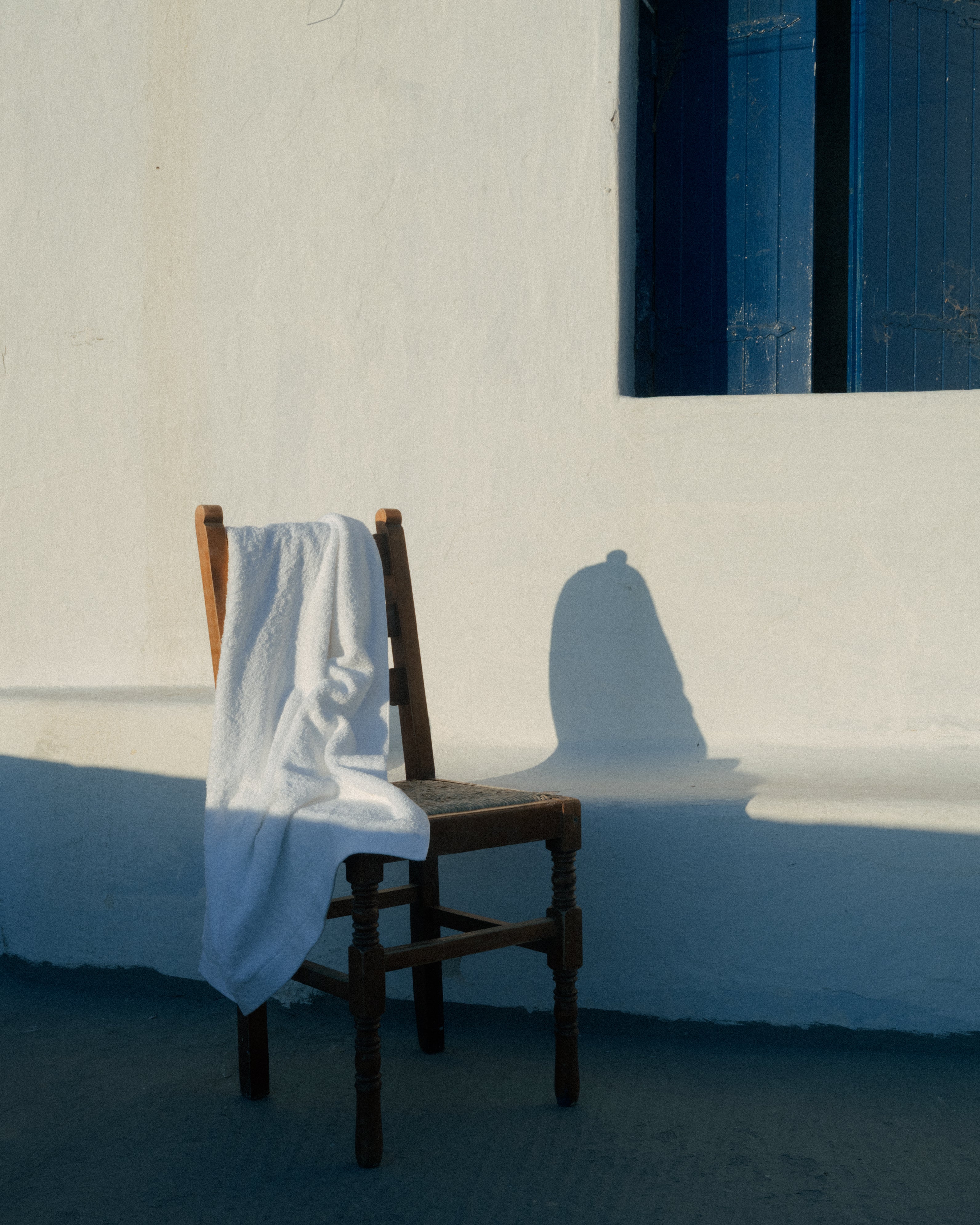 Old brown wooden chair with a towel on it, photographed on Mykonos.